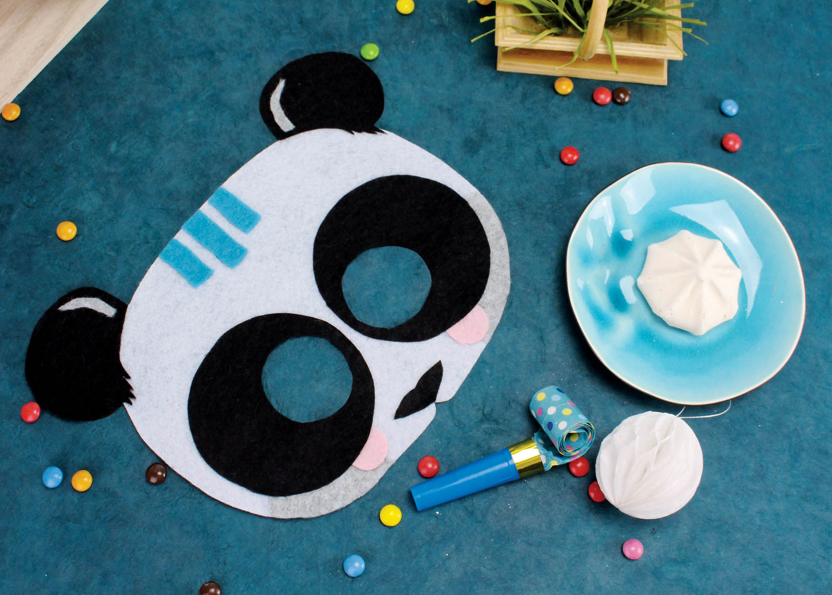 Masque panda en feutrine décoré sur fond bleu avec smarties et meringue