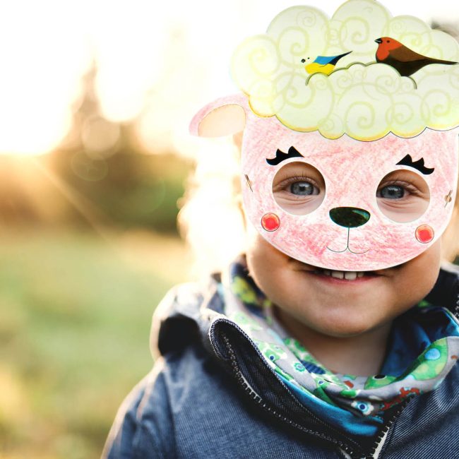 Enfant qui porte un masque mouton colorié avec fond vert