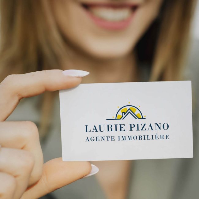 Femme souriante tenant une carte de visite d'agente immobilière avec logo