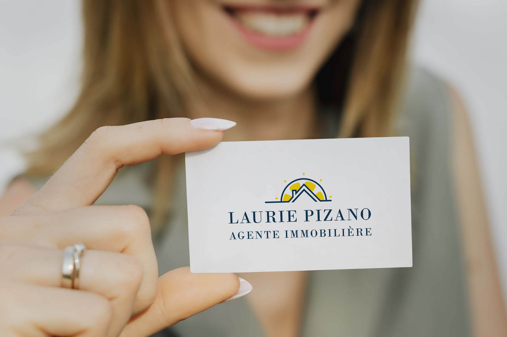 Femme souriante tenant une carte de visite d'agente immobilière avec logo