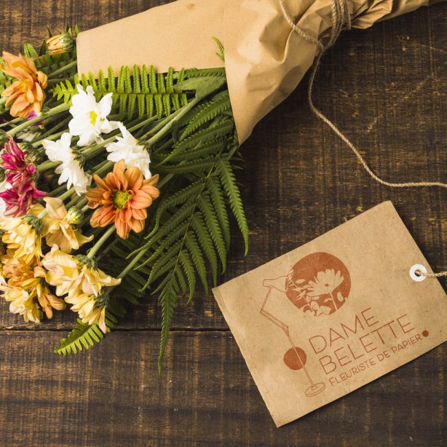 bouquet de fleurs entouré d'un papier kraft avec carte de visite avec logo