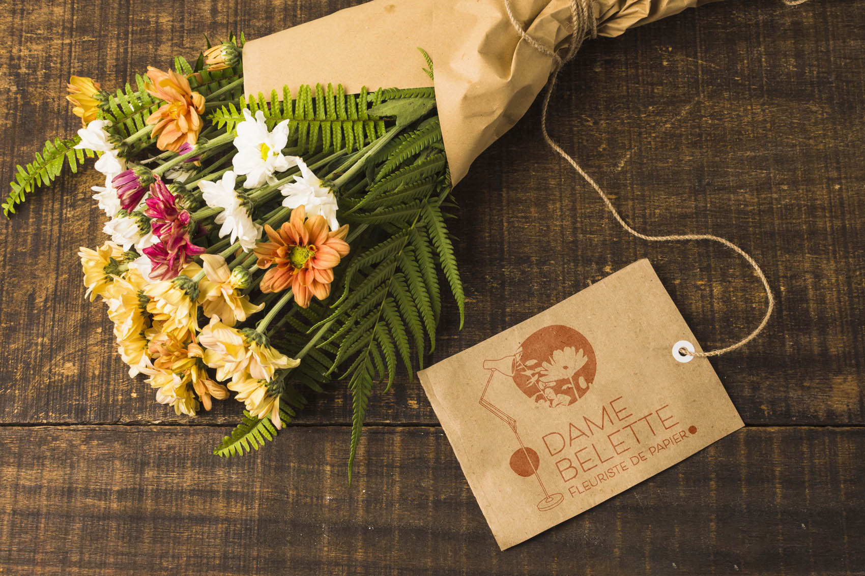 bouquet de fleurs entouré d'un papier kraft avec carte de visite avec logo