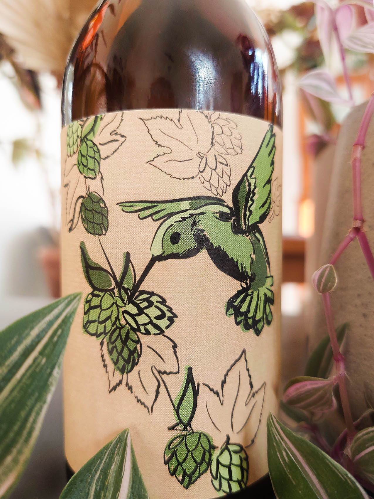 Etiquette kraft sur bière artisanale, avec colibri vert qui vole autour du houblon.