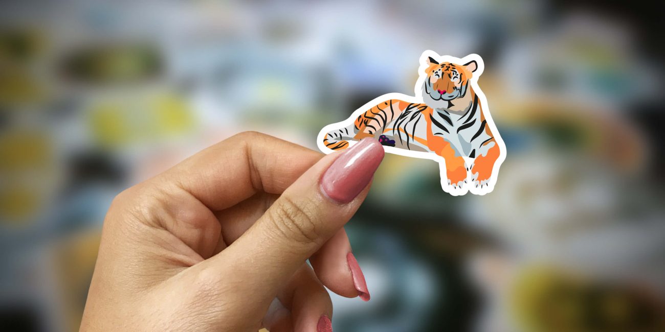 Main de femme qui tient un sticker tigre dans les mains