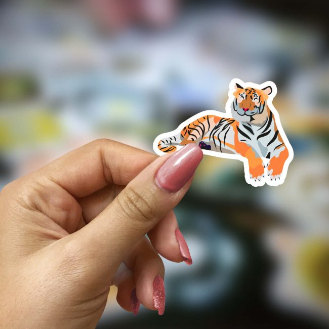 Main de femme qui tient un sticker tigre dans les mains