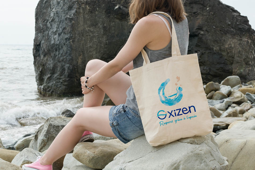 Création de logo sur totebag porté par femme en bord de mer